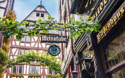 Fachwerkhaus mit Weinstube und Efeu-bewachsenen Schildern in einer Altstadt.