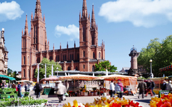 Marktplatz mit gotischer Kirche und Verkaufsständen im Freien.