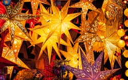 Bunte leuchtende Papiersterne auf einem Weihnachtsmarkt.
